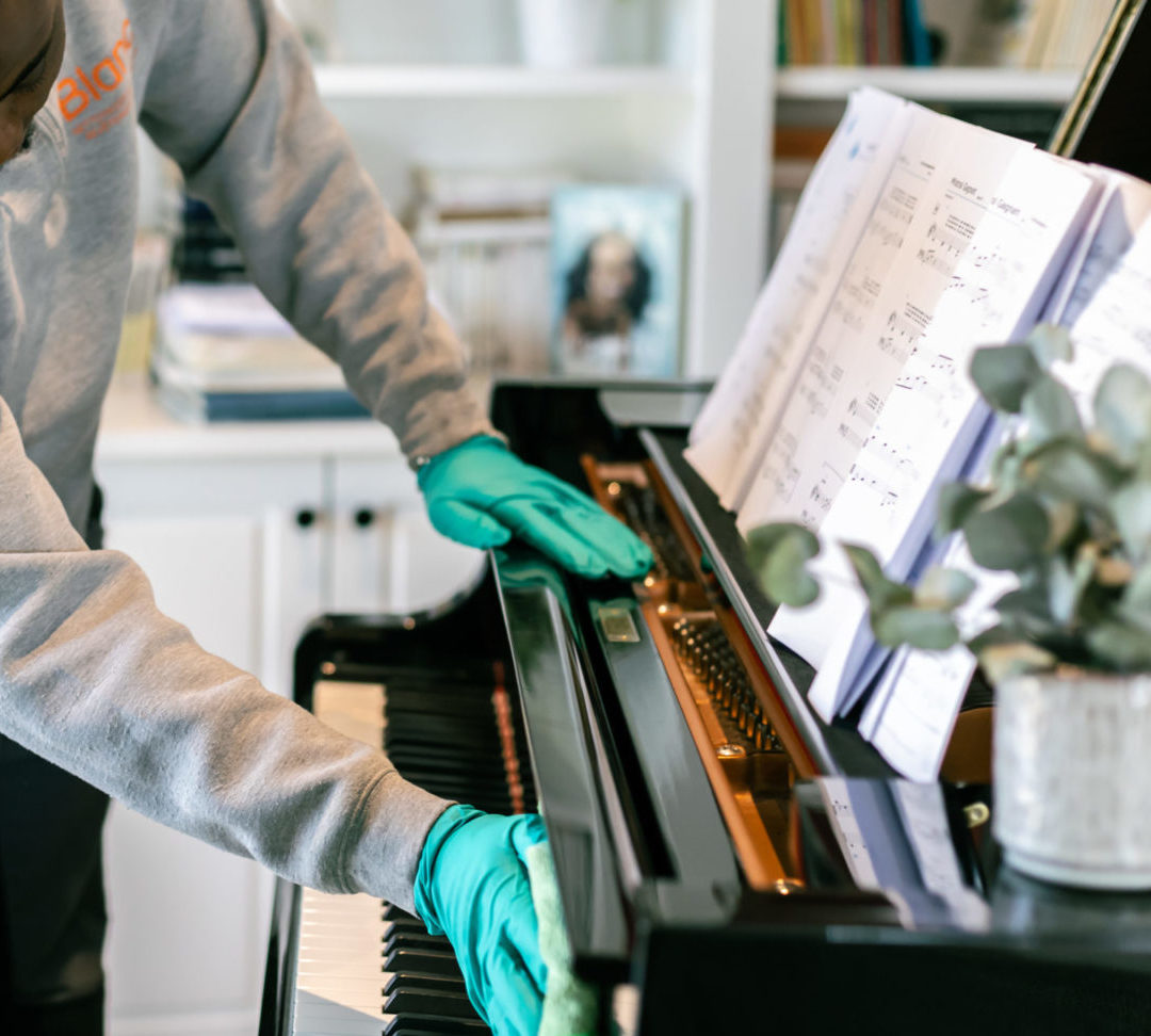 Agent Blanc SA nettoyant les touches et le cadre d'un piano à queue